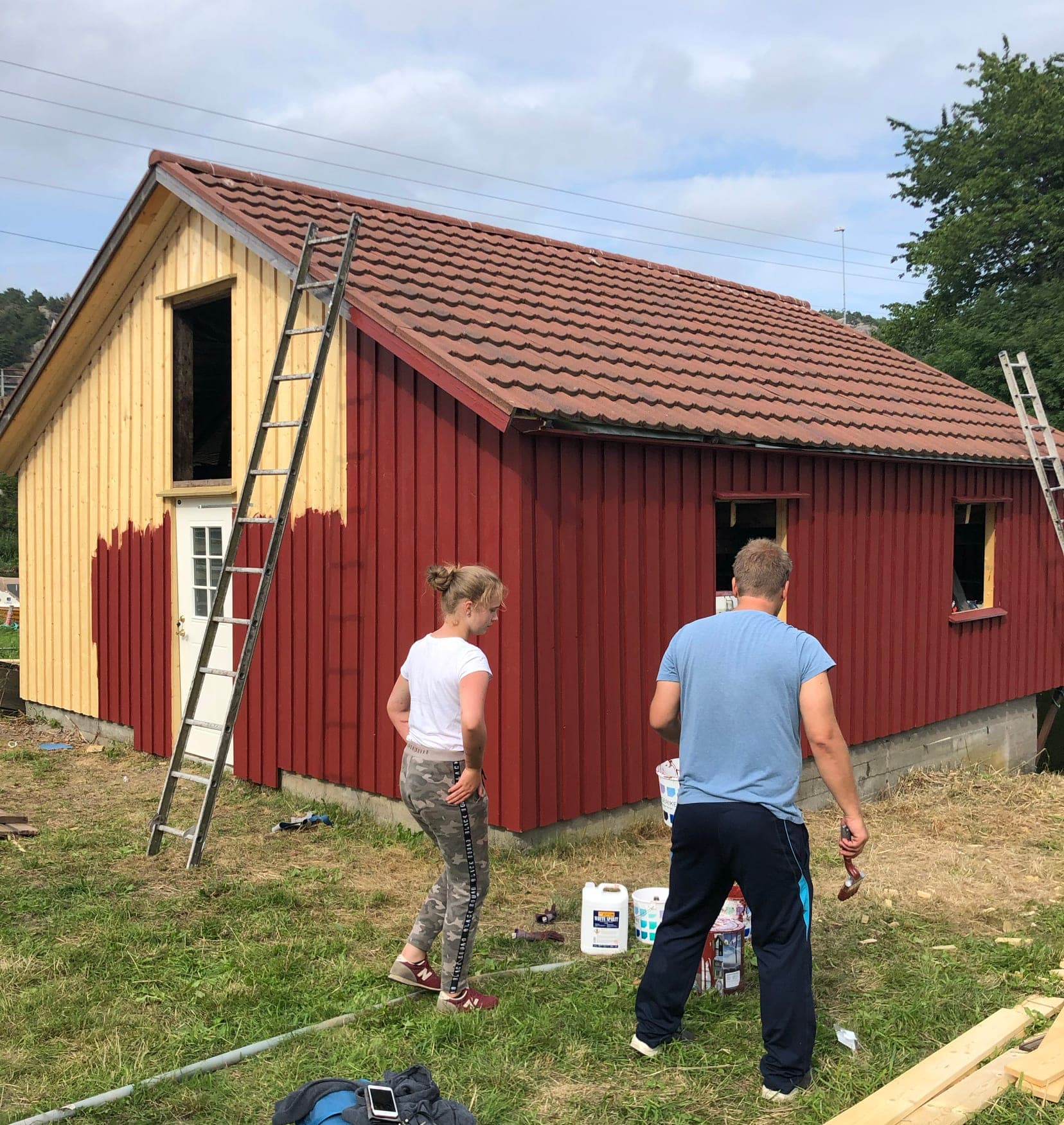 To personer maler et naust på Sørlandet en sommerdag